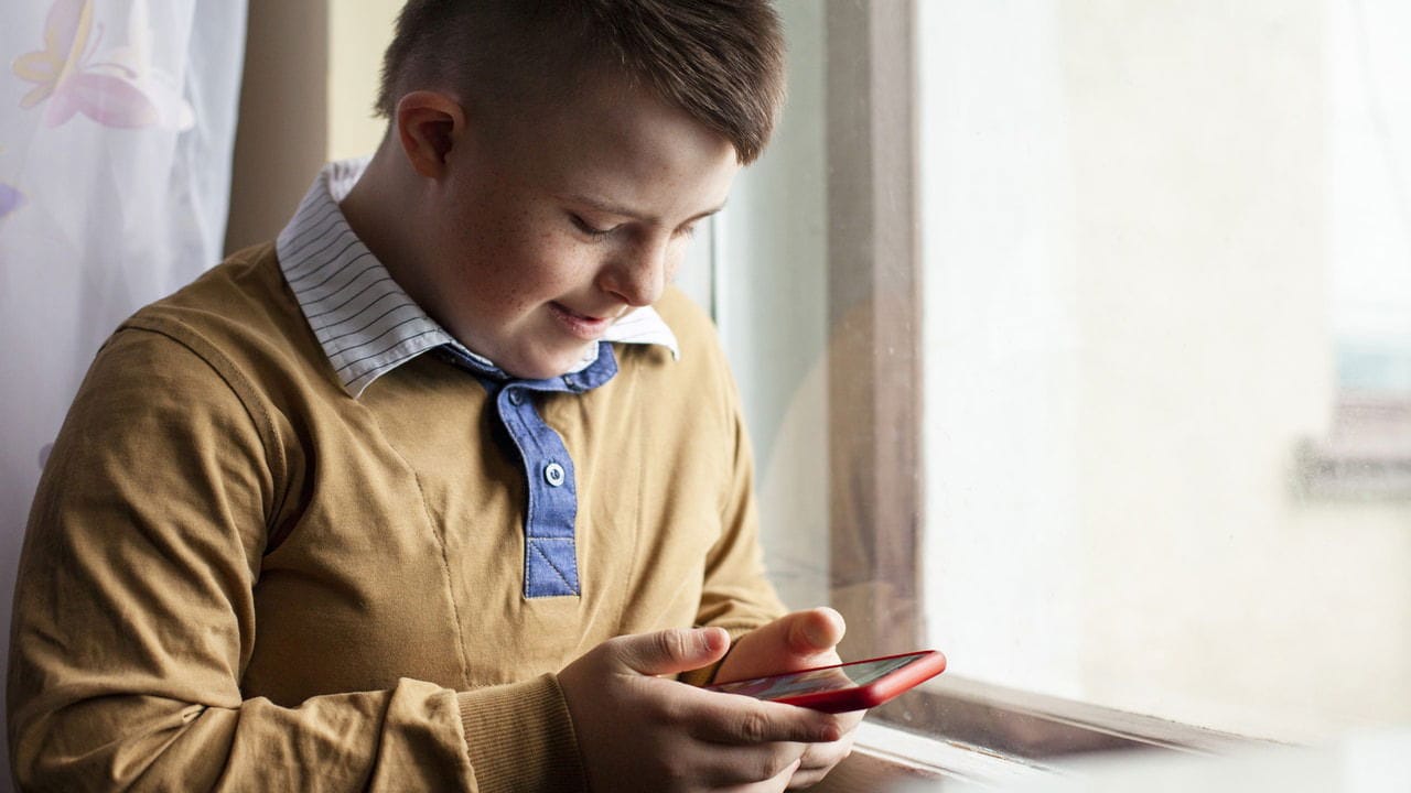 Young boy happily using phone near a window