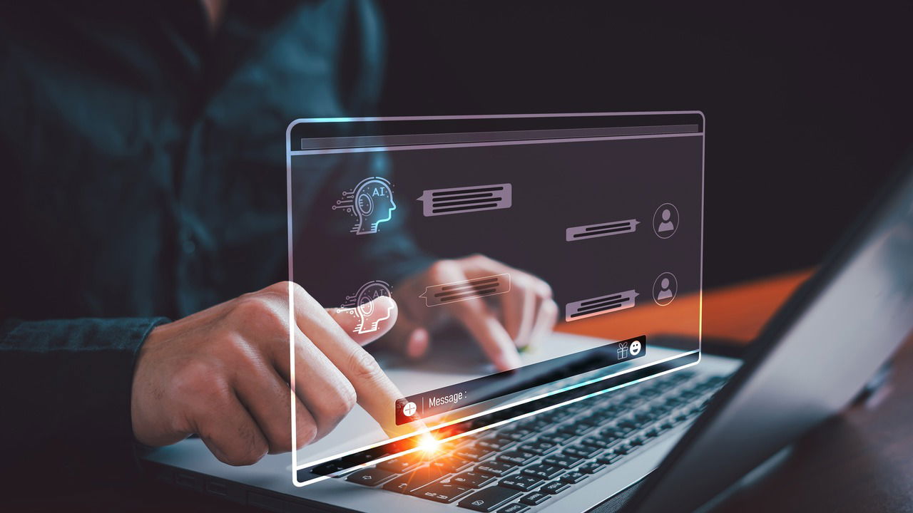 a person taping on laptop keyboard with AI conversation on hologram UI