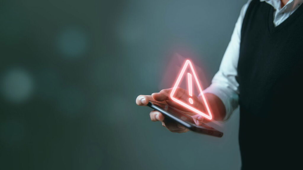 person holding a phone with an alert icon on top