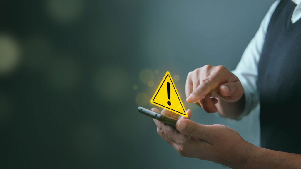 Man using a phone with a caution icon hologram