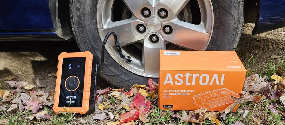 AstroAI S8 Jump Starter et boîte à côté du pneu.
