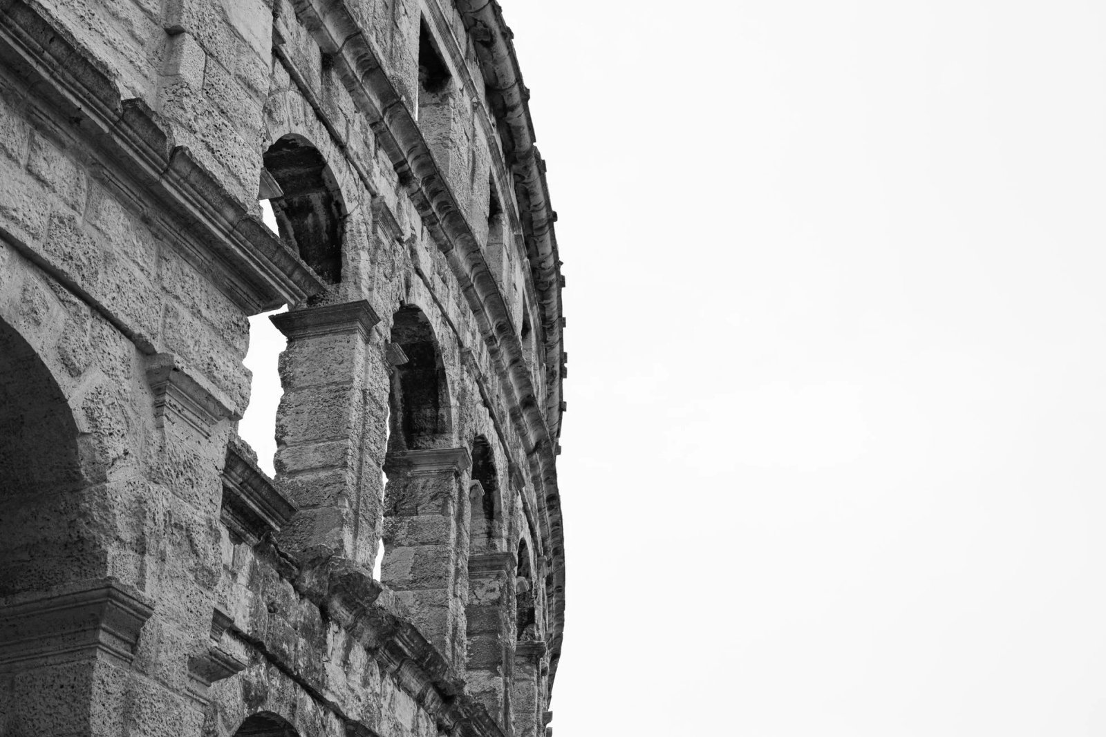 Image en noir et blanc d’un colisée historique en pierre présentant une architecture ancienne.