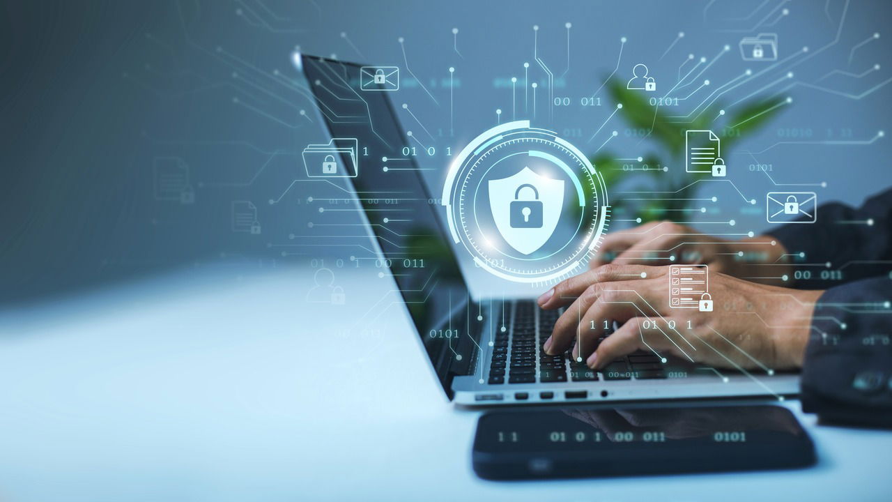 man using laptop on table with security lock hologram in front