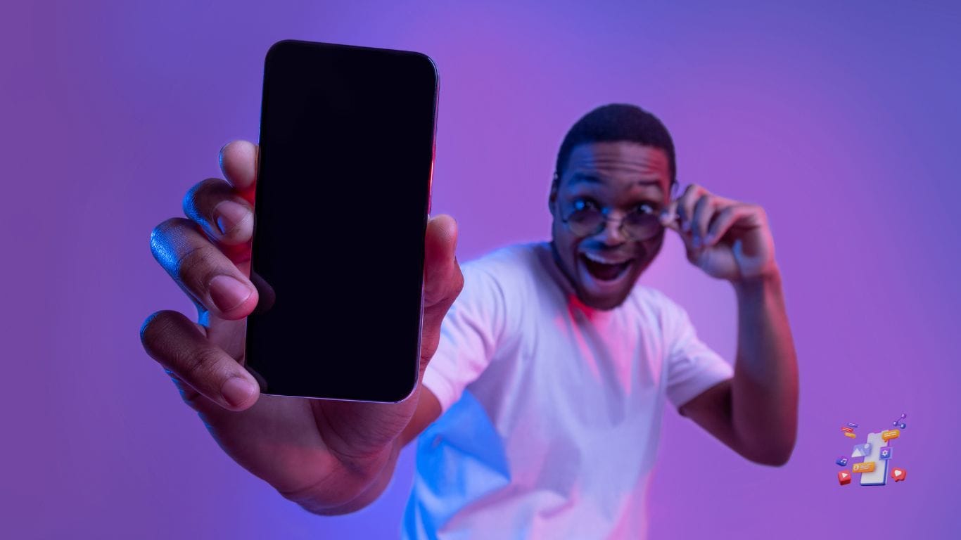 un homme avec des lunettes qui tient en main son nouveau smartphone qu'il montre à la caméra